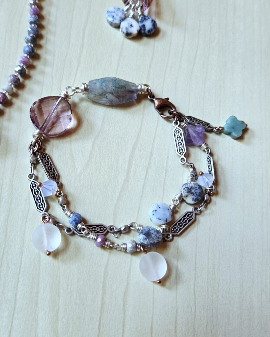 Mixed gemstone bracelet featuring fluorite, dendritic opal, quartz, sapphire, and an amethyst quatrefoil bead, with an amazonite charm and sparkling Swarovski crystals.