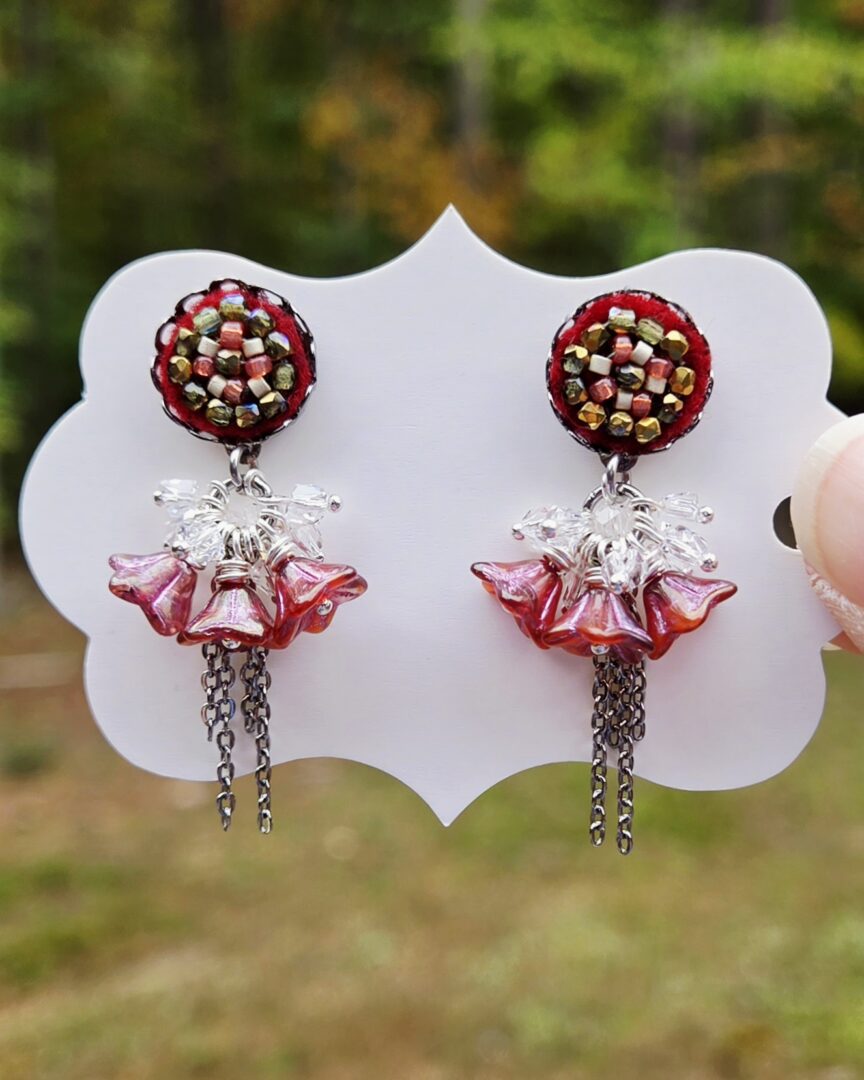 Floral dangle earrings with Swarovski crystals, featuring hand-stitched on maroon felt seed bead earring posts with frosted ruby Czech glass bell flowers, and delicate silver chain details.